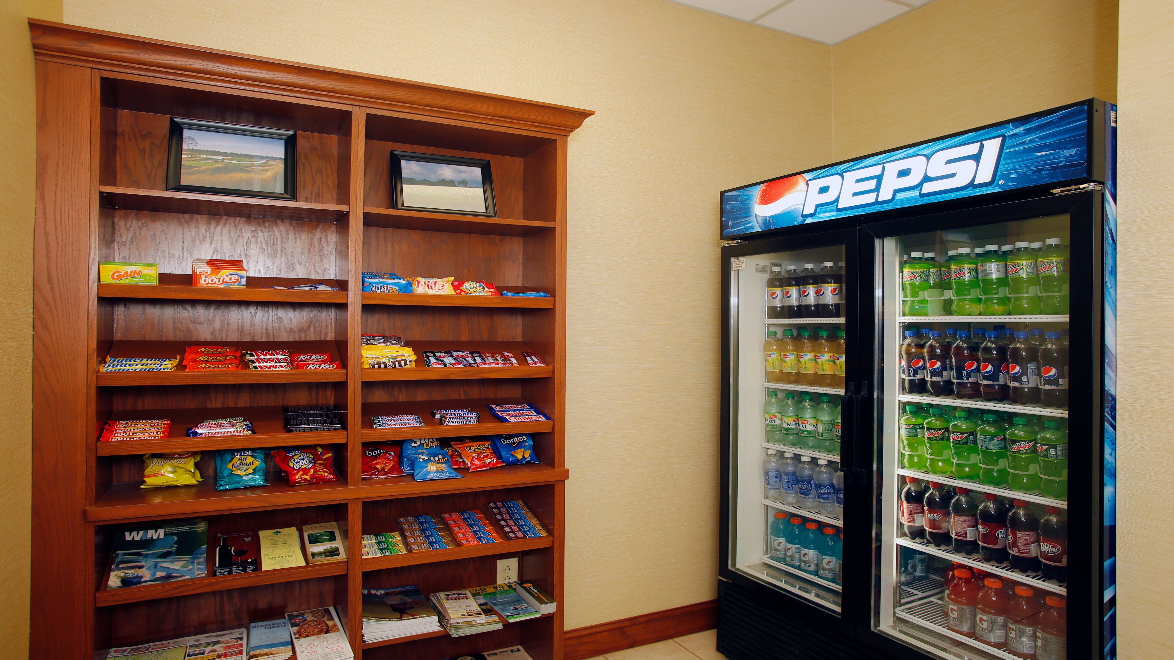 A vending machine stocked with various beverages and snacks, and a wooden shelf unit with packaged food items.