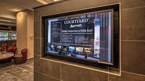 A digital display in a hotel lobby advertising Courtyard Marriott with amenities and new additions. - Courtyard by Marriott Dulles Airport Herndon (Herndon)