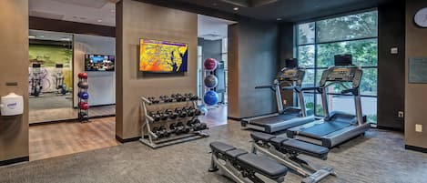 A gym with treadmills, dumbbells, and exercise balls.