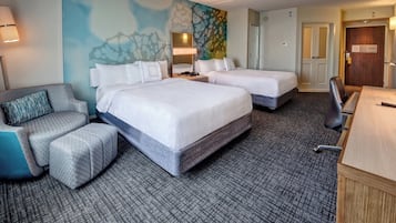 A hotel room with two beds, a desk, a chair, and a couch.