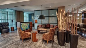 A modern lobby with a large TV, comfortable seating, and decorative vases. - Courtyard by Marriott Dulles Airport Herndon (Herndon)