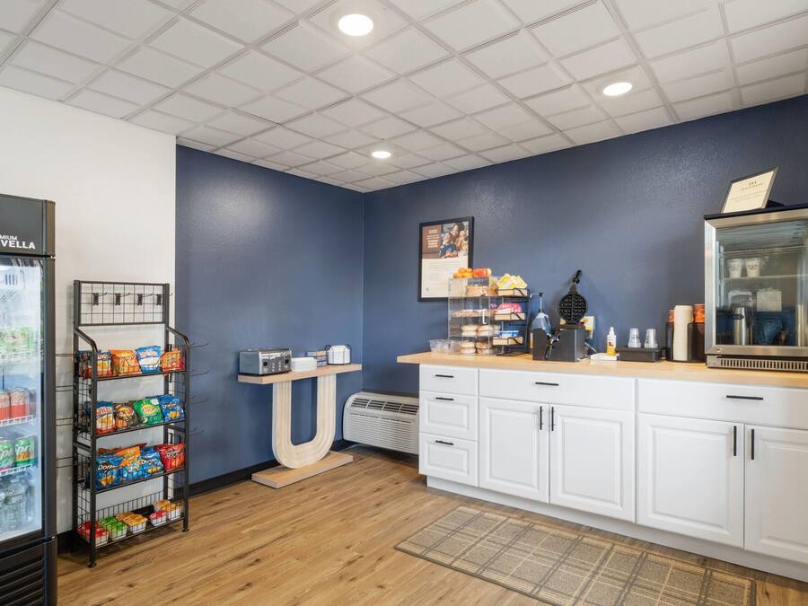 A kitchenette with a refrigerator stocked with beverages, a snack shelf, a coffee maker, and a microwave.