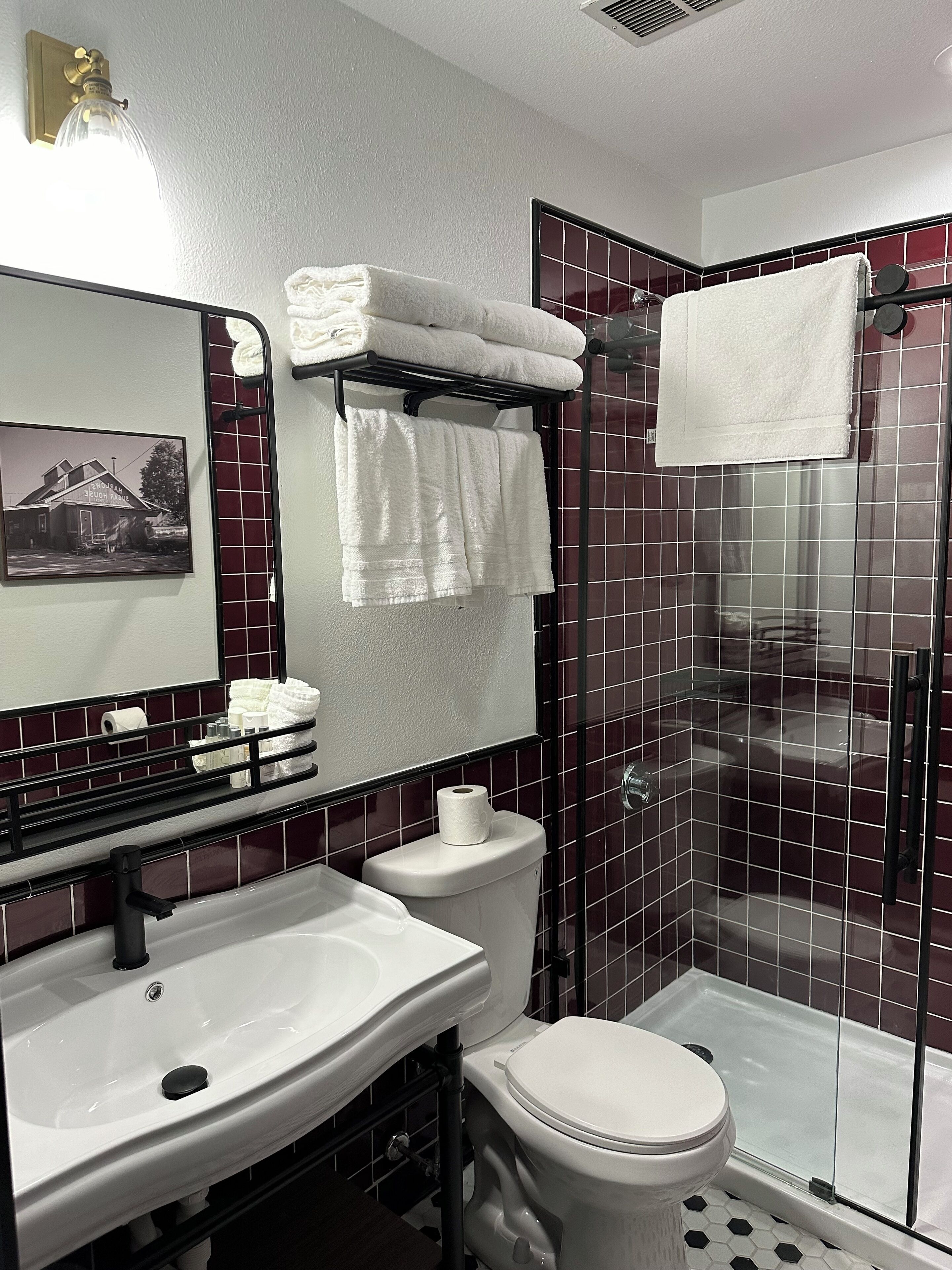 Un baño con lavamanos blanco, inodoro, cabina de ducha de vidrio y espejo con marco.