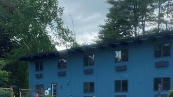 A blue building with a swimming pool, surrounded by trees.