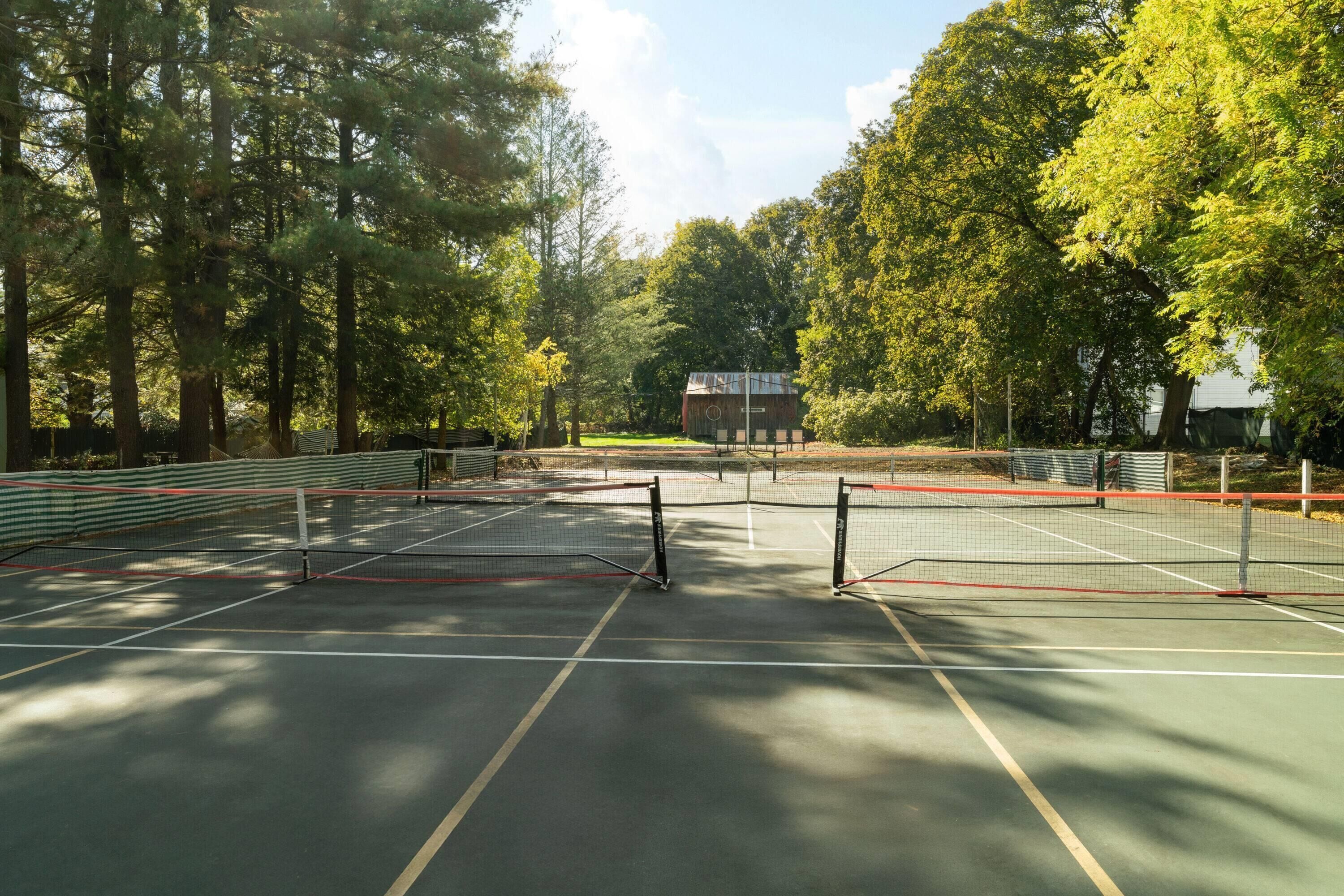 Un court de tennis en plein air, entouré d’arbres.
