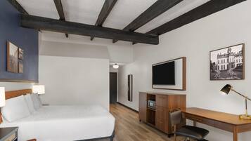 Une chambre d’hôtel équipée d’un lit, d’un bureau, d’une chaise et d’un téléviseur.