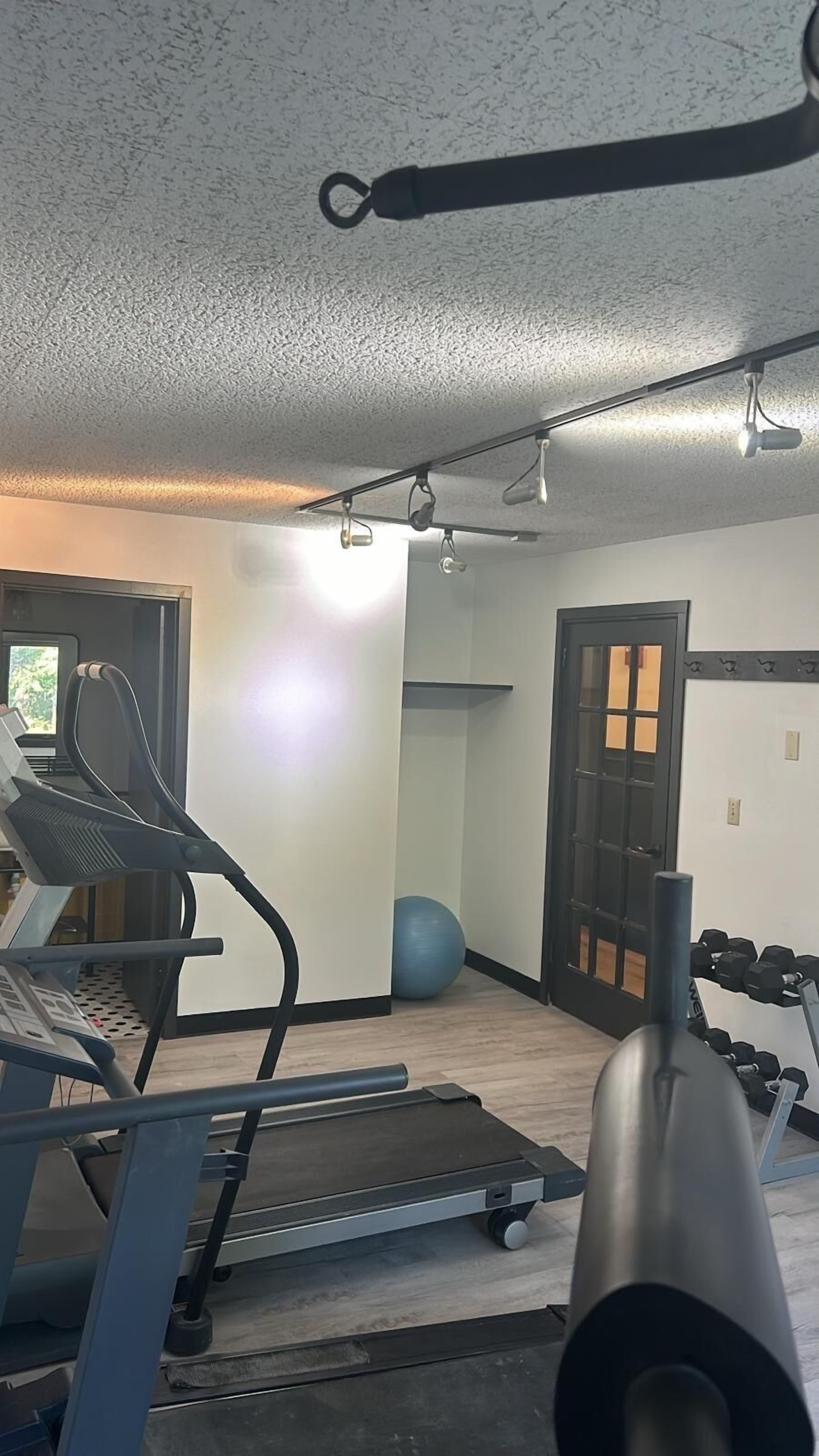 A gym with exercise equipment including treadmills, a stationary bike, and dumbbells.
