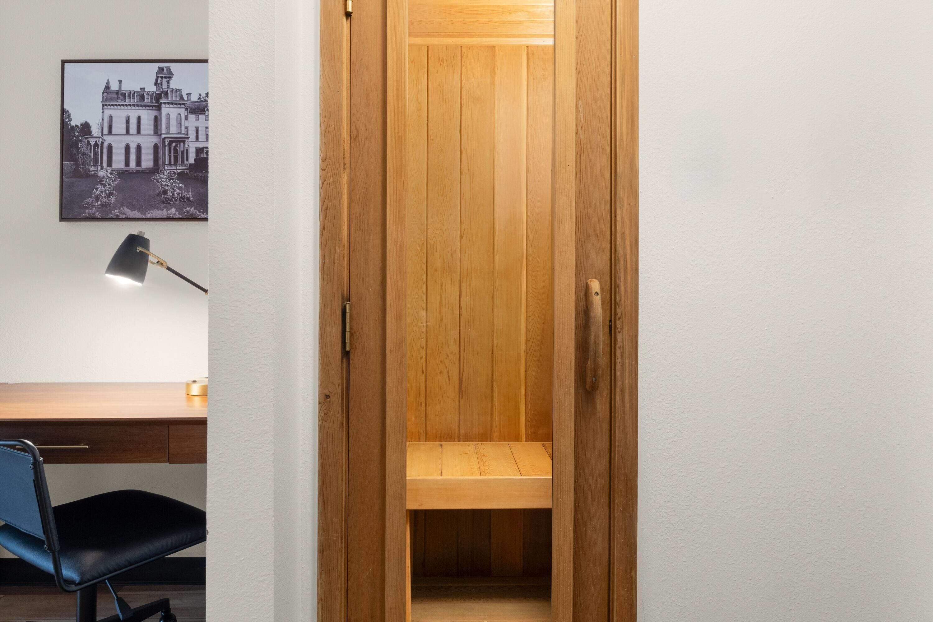 Une armoire en bois avec un miroir, un bureau avec une chaise et un tableau encadré accroché au mur.