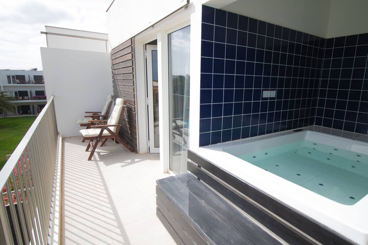 A balcony with a seating area and a spa tub.