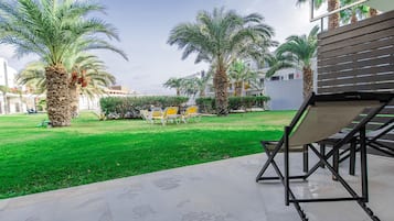 Un patio con palmeras, asientos al aire libre y un edificio al fondo.