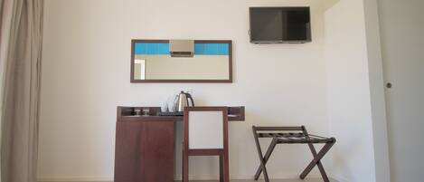 A small room with a desk, chair, and a TV mounted on the wall.