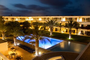 A hotel with a swimming pool, palm trees, and outdoor seating areas. - Hotel Dunas de Sal (Sal)