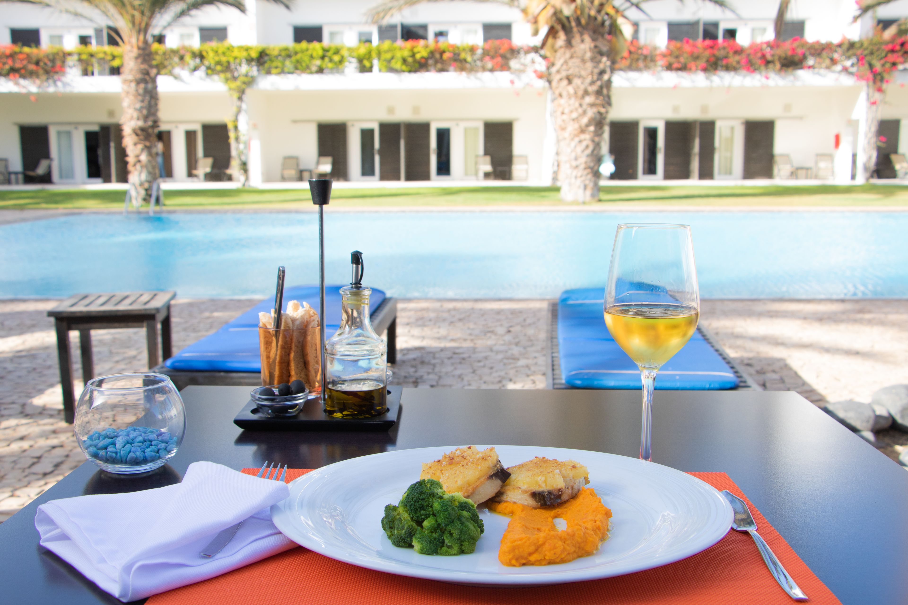 Una mesa de comedor con un plato de comida, una copa de vino y un bol de caramelos azules.