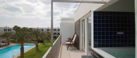 Un balcon avec une piscine, des palmiers et une vue sur d’autres immeubles.