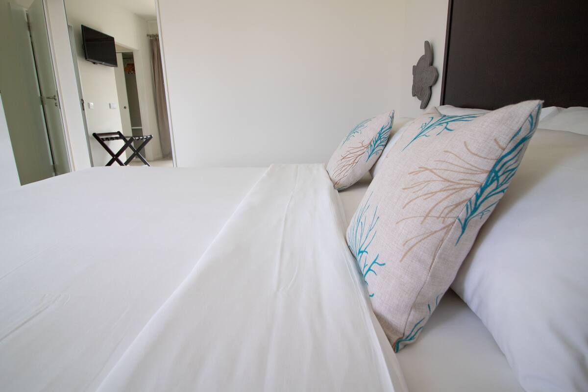A neatly made bed with white linens and decorative pillows with leaf patterns.