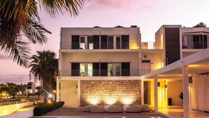A modern building with a pool, stone wall, and outdoor seating. - Hotel Dunas de Sal (Sal)