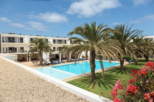Una piscina al aire libre, sombrillas, sillones reclinables de piscina