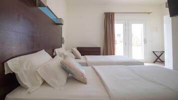 A hotel room with two beds, a wooden headboard, and a view of the outdoors through a door.