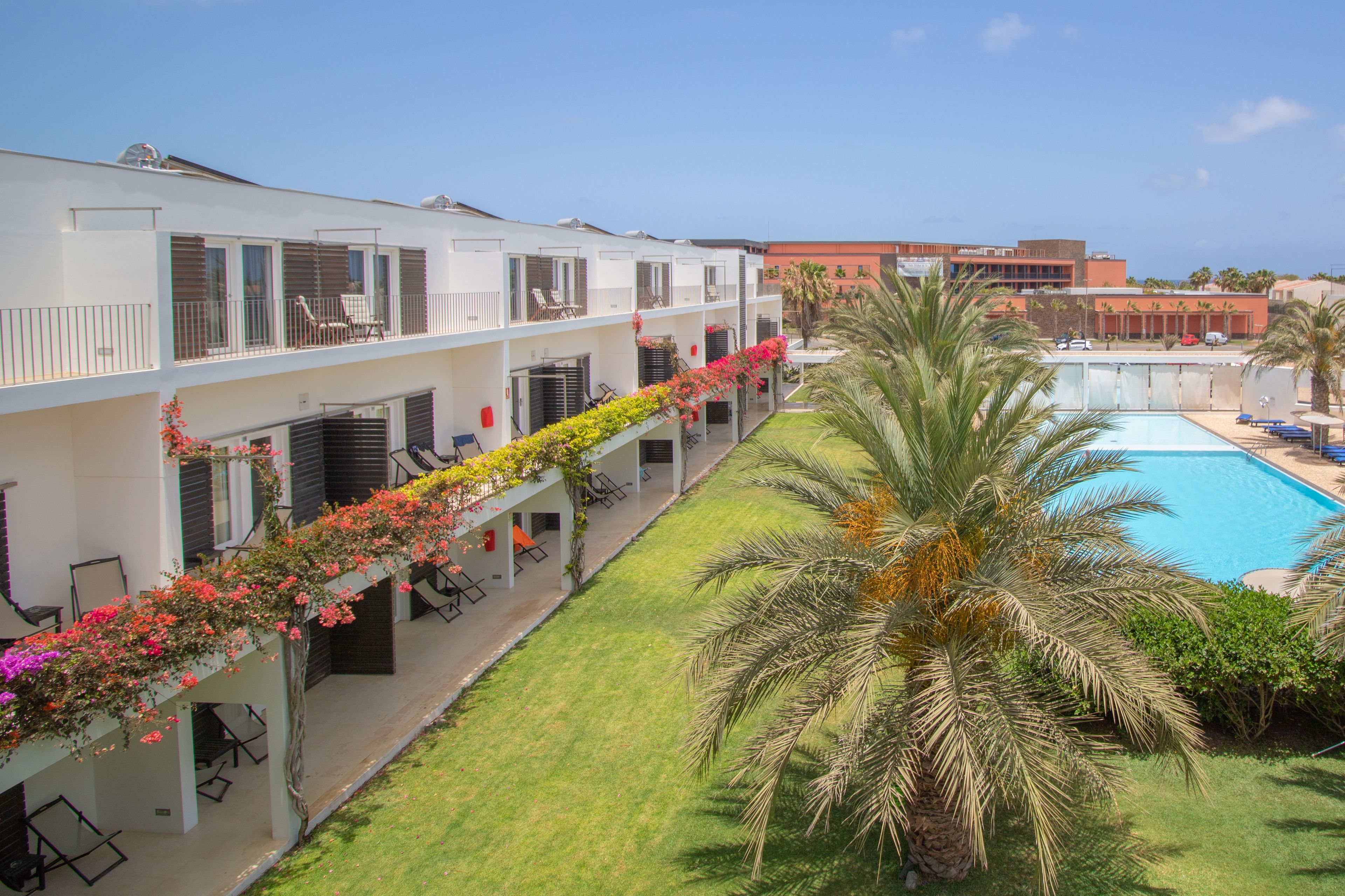 Un hotel con piscina, area relax all'aperto e prato curato.