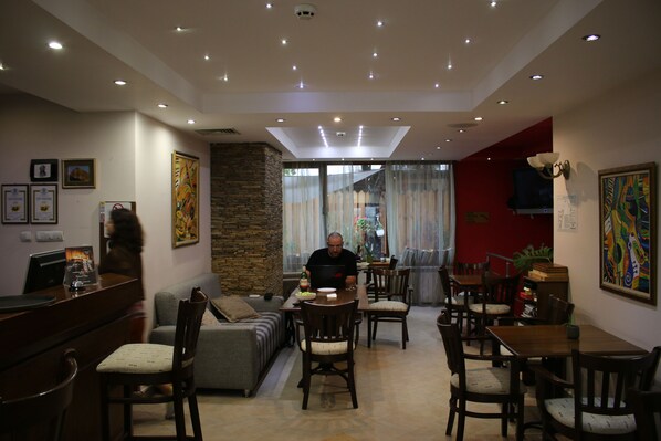 A modern living room with a dining area, featuring a sofa, dining table, and chairs. - Hotel Kralev Dvor (Bansko)