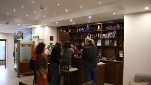Eine Bar mit Holzböden, die mit Flaschen gefüllt sind, ein Empfangstresen und einige Gäste.