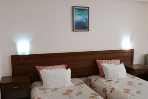 Una cama doble con ropa de cama floral, dos mesitas de noche y un cuadro en la pared.