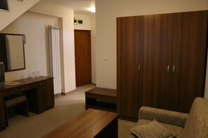 A room with a wooden desk, a sofa, a wardrobe, and a shower area. - Hotel Kralev Dvor (Bansko)