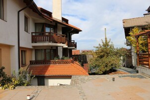 Un edificio de varios pisos con balcones, techo de tejas y un patio con baldosas de piedra.