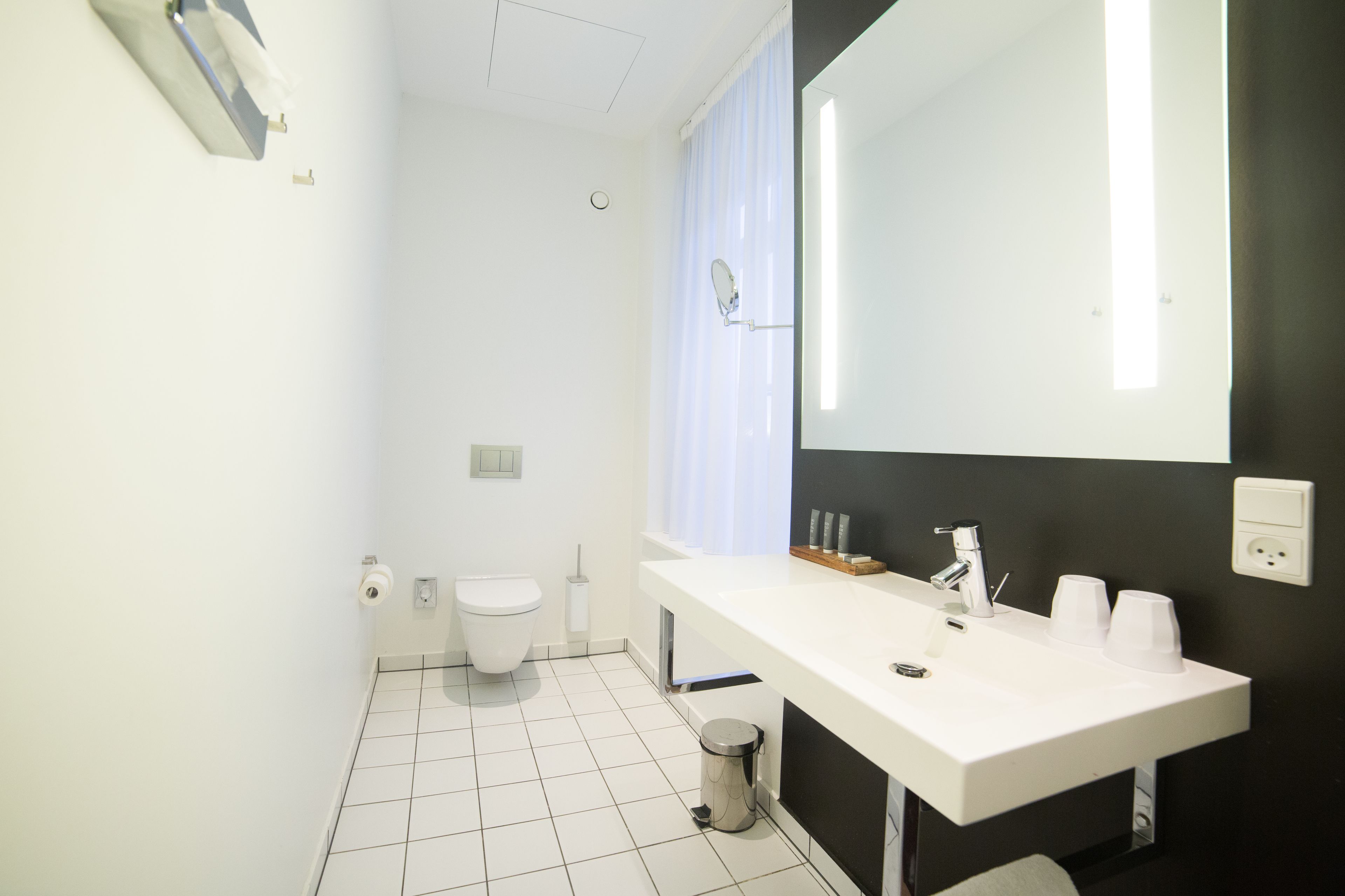 Een moderne badkamer met een wit wastafelmeubel, spiegel en toilet.