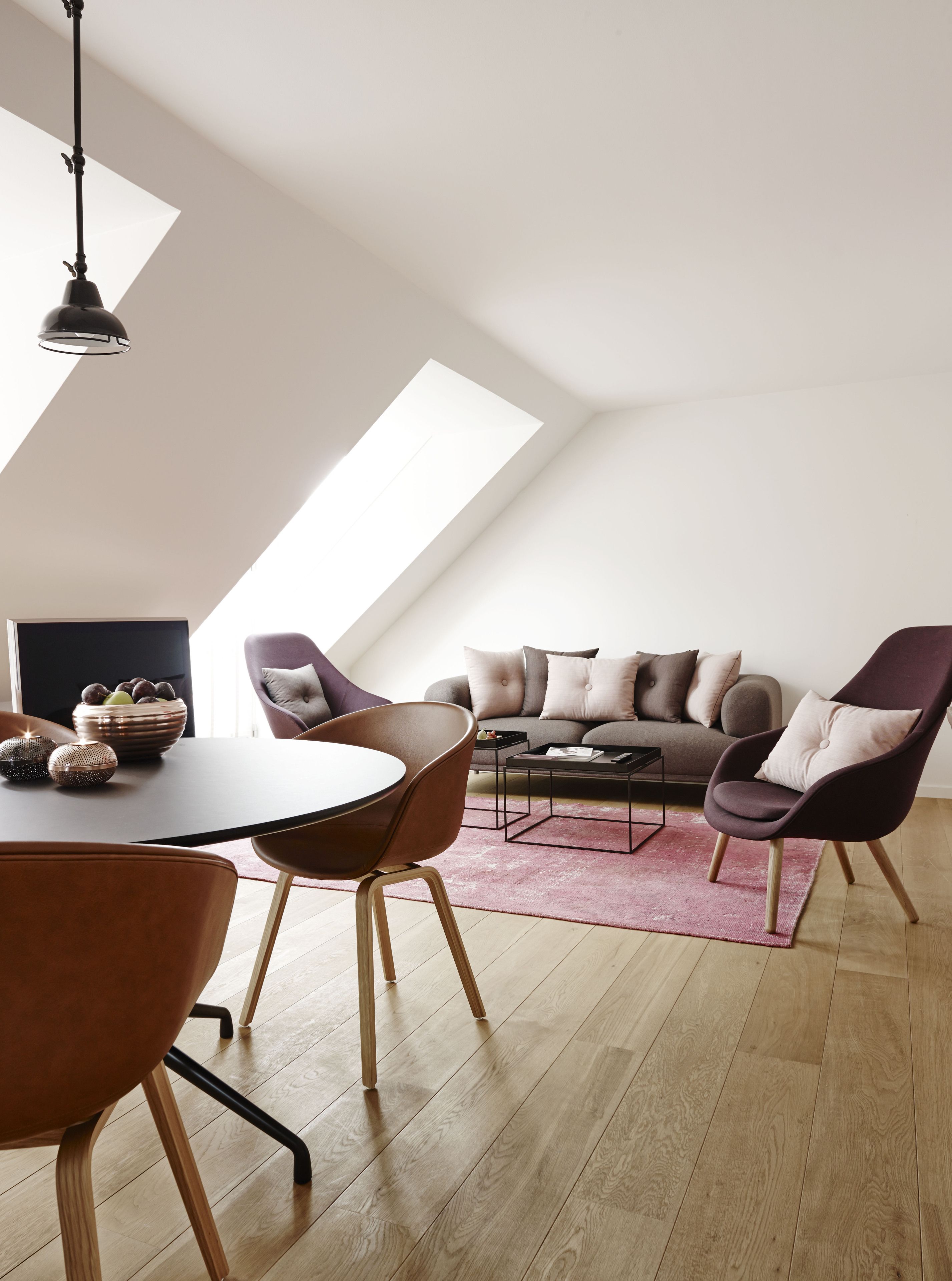 A modern loft with a dining area, a sofa set, and a large window providing natural light.