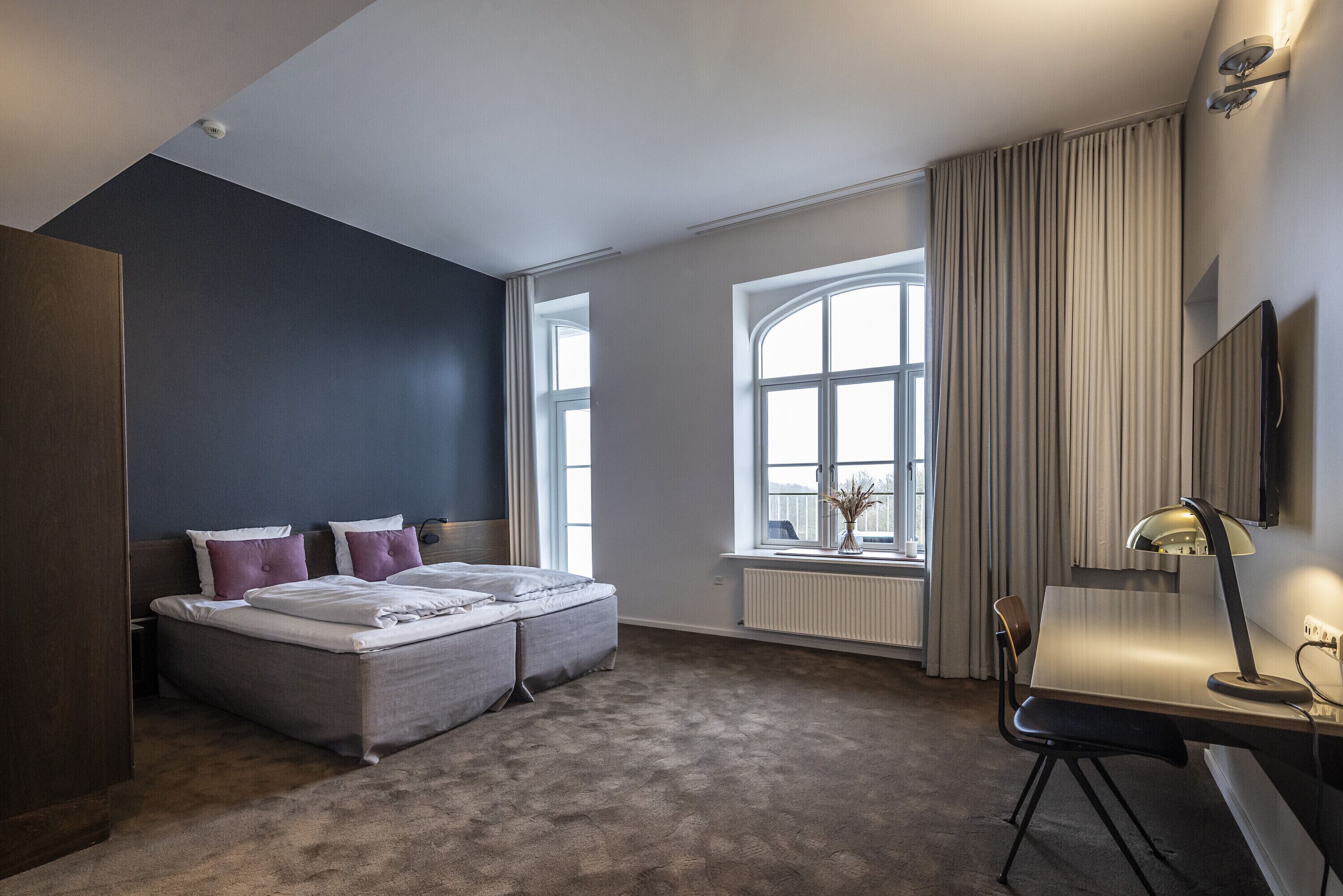 A modern bedroom with a bed, a desk, and a chair.