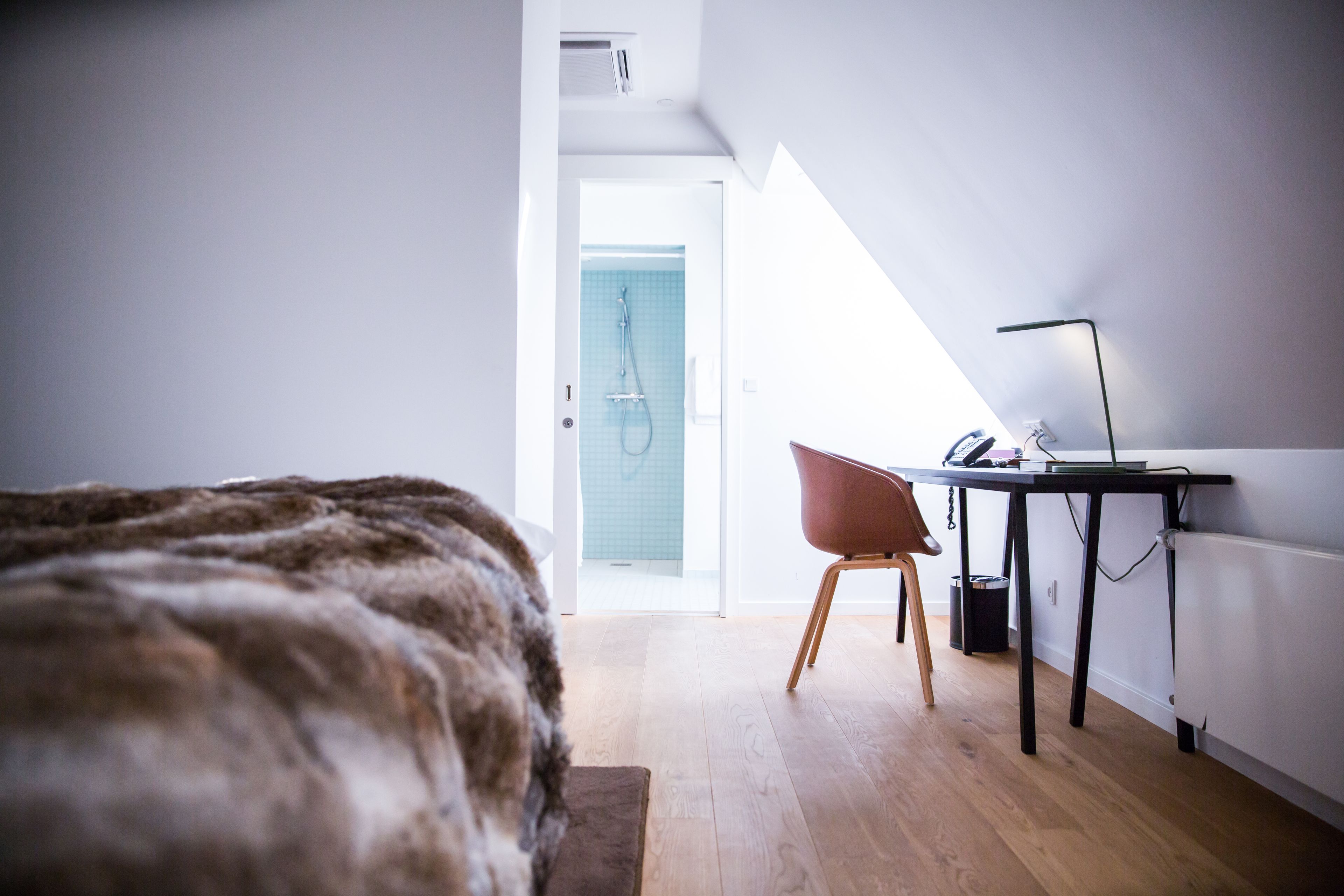 Un dormitorio con una cama grande, un escritorio con una silla y vistas a un baño con ducha.