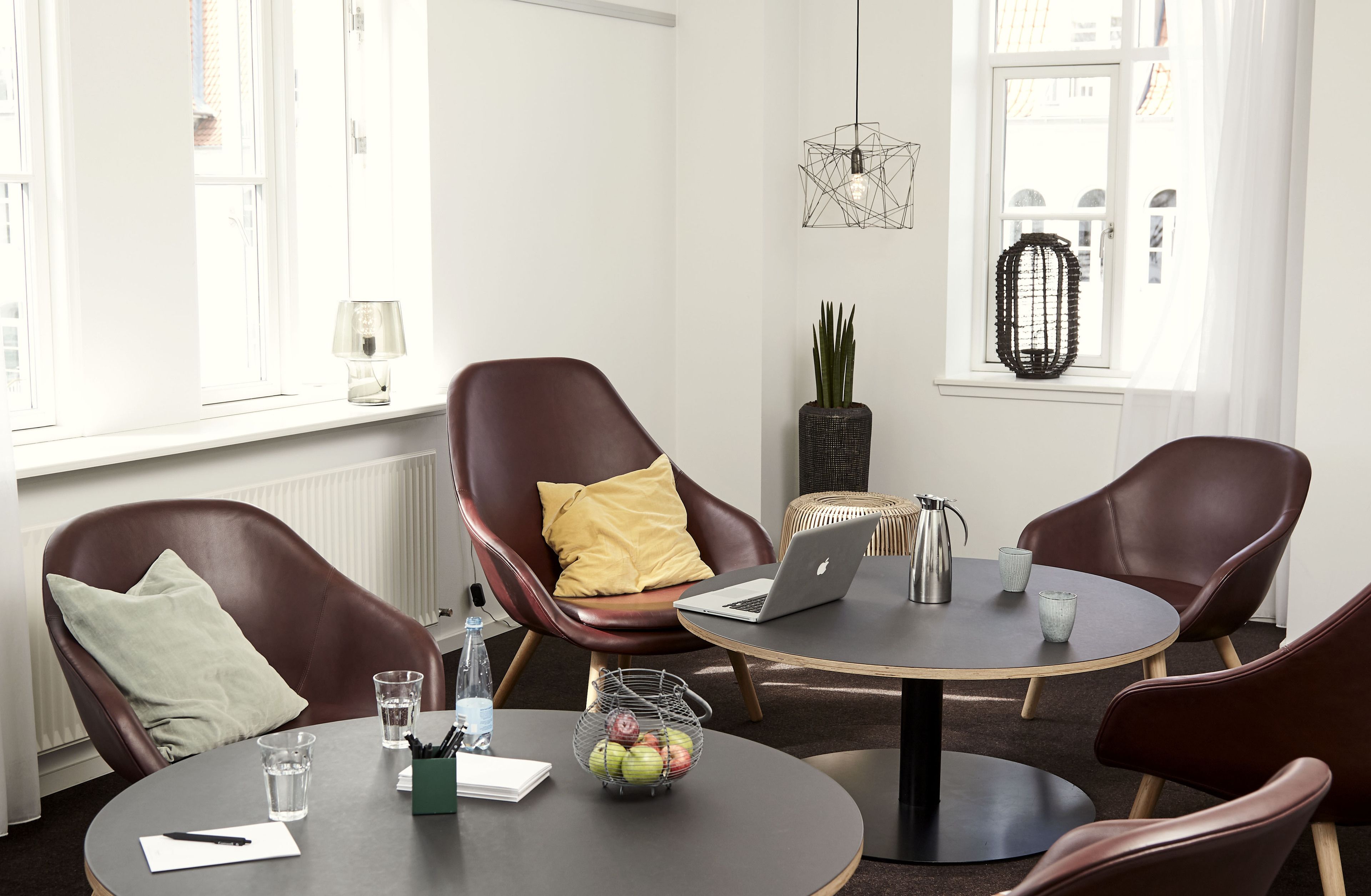 A modern meeting room with leather chairs, a round table, and a laptop.