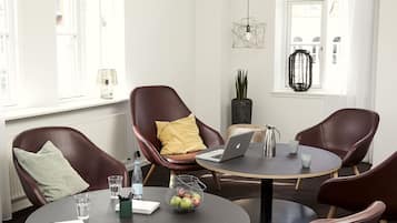 A modern meeting room with leather chairs, a round table, and a laptop.