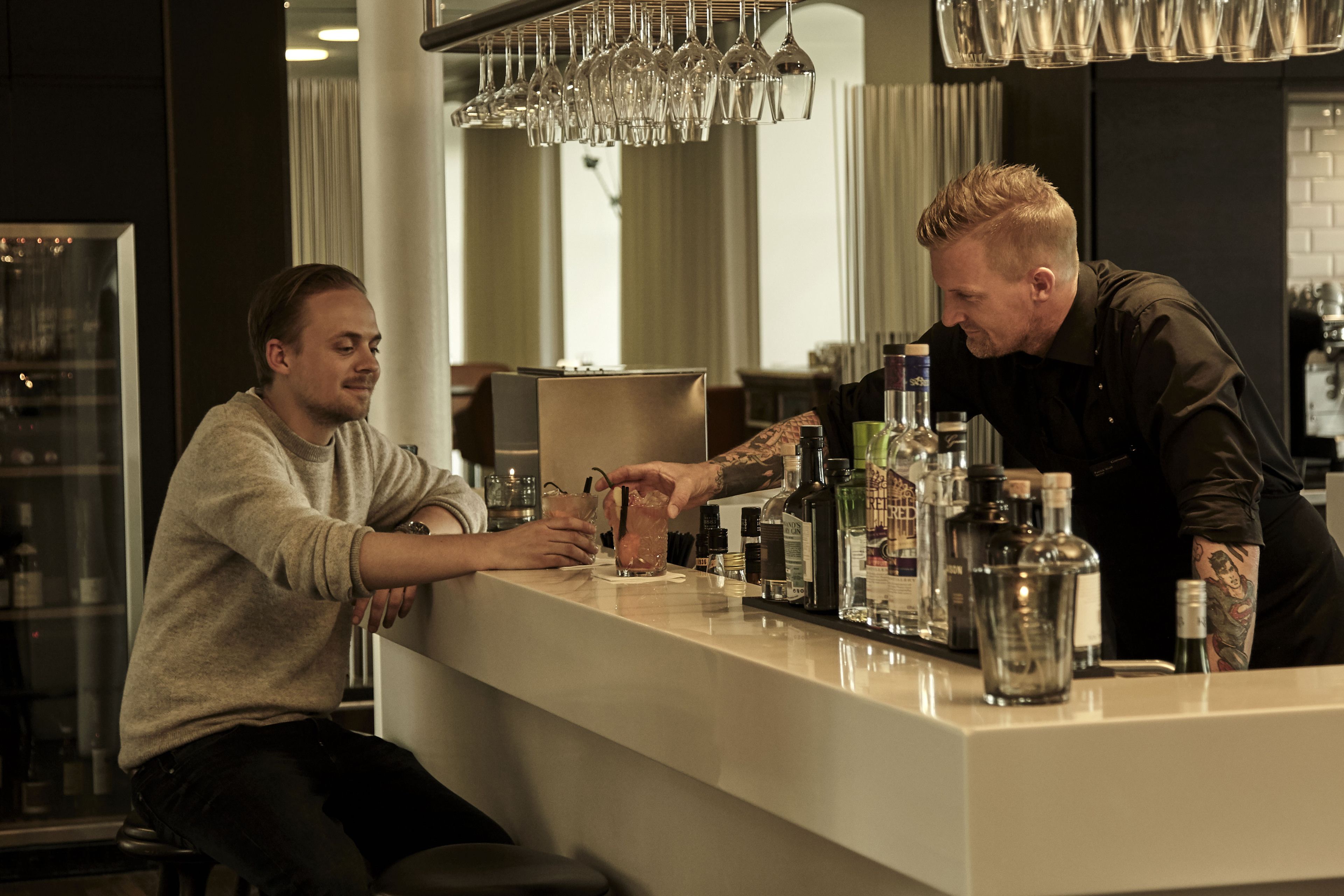 A bar area with a counter, glasses, and bottles.