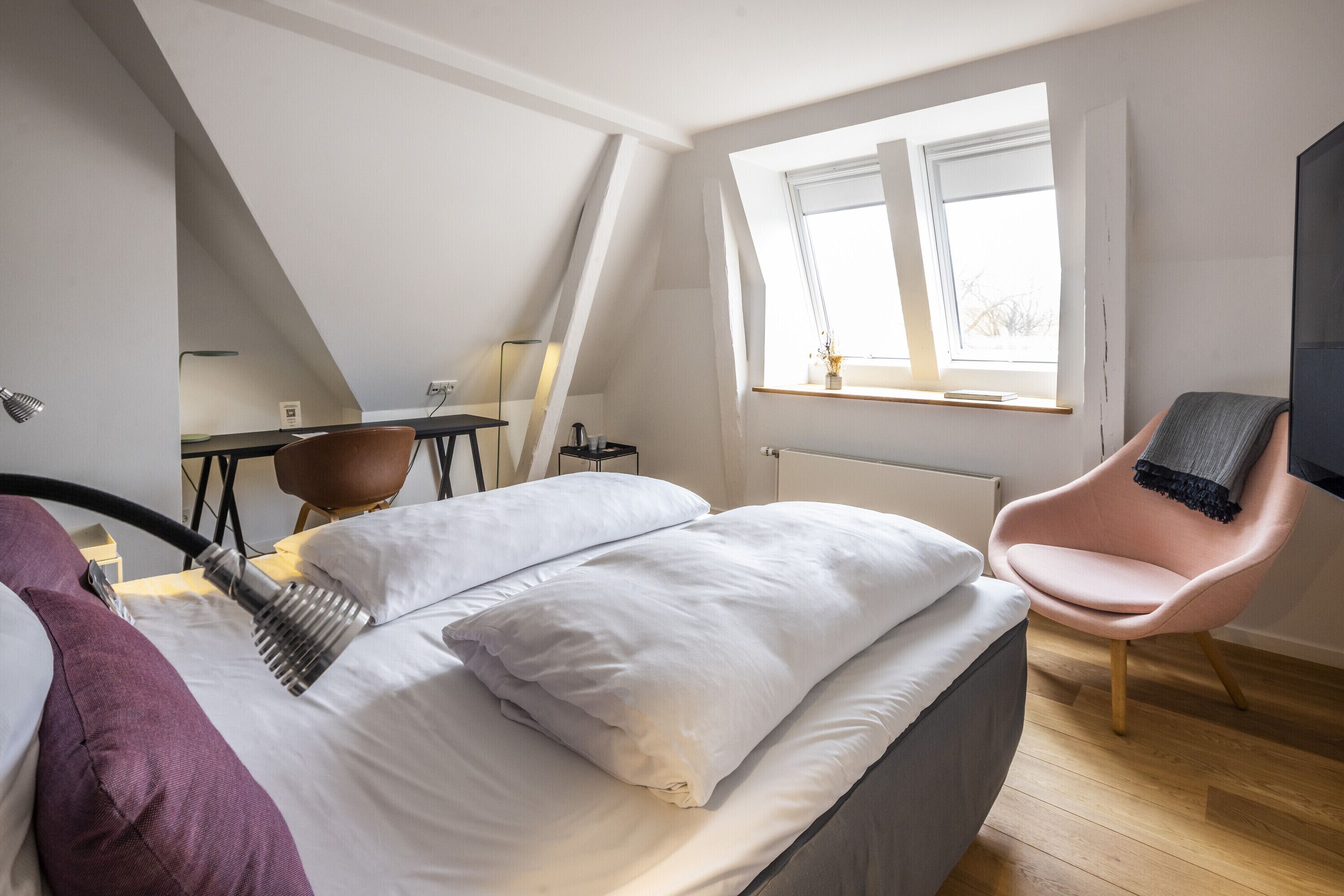 Une chambre à coucher moderne avec un lit, une chaise, un bureau et une fenêtre.