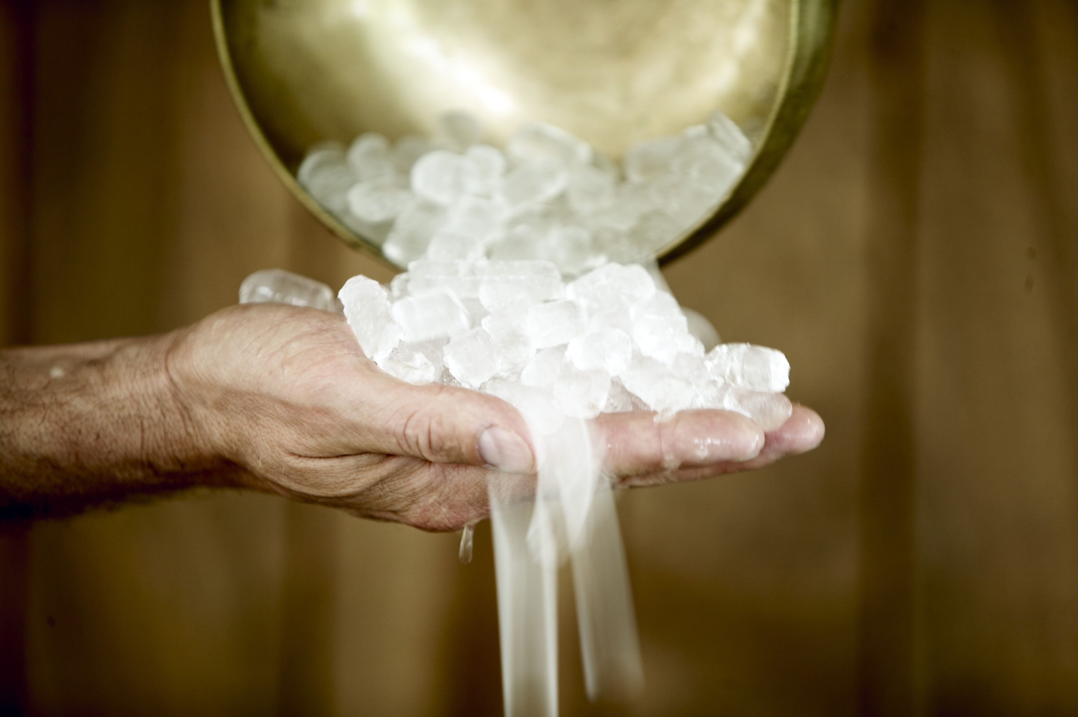 A hand holding a bowl of ice cubes.