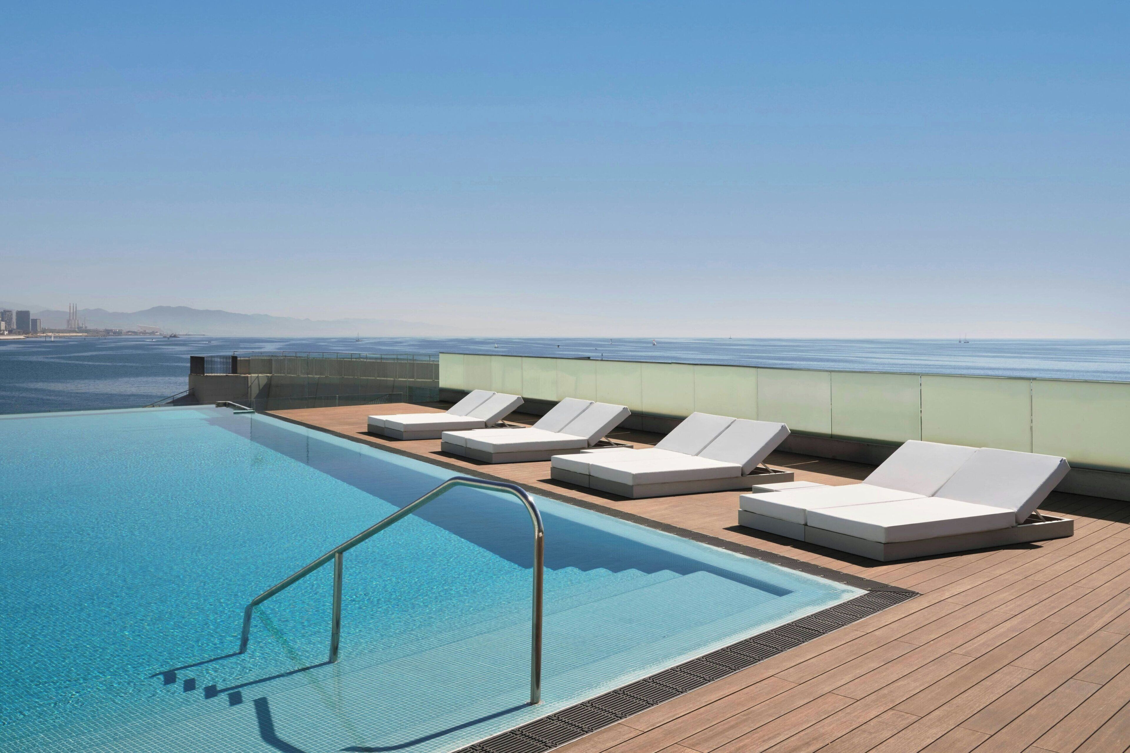 Una piscina en la azotea con sillones de descanso y vistas al océano.