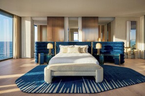 A spacious bedroom with a large bed, two bedside tables, and a view of the ocean.