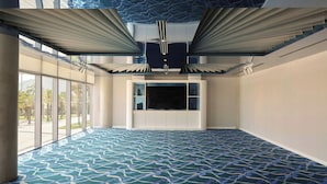 Una habitación amplia con alfombra estampada, ventanas grandes y un techo de diseño único.