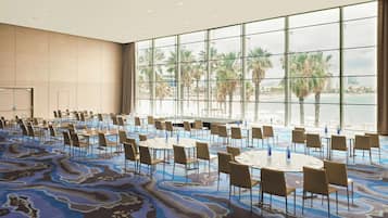 Une salle de conférence avec vue sur les palmiers et la plage.