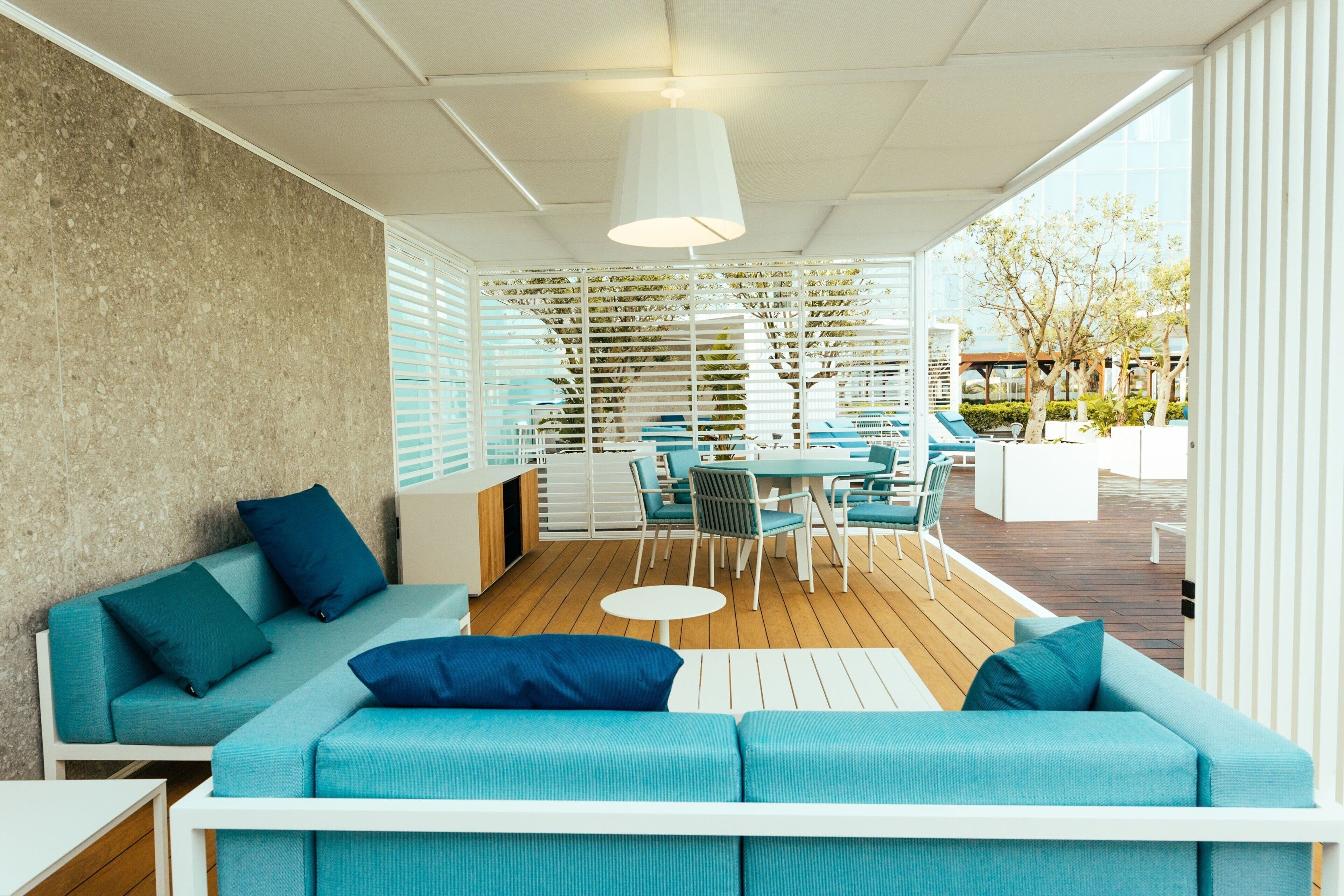 Un espacio al aire libre moderno con zona de estar, sofá, sillones, una mesa y un ventilador de techo.
