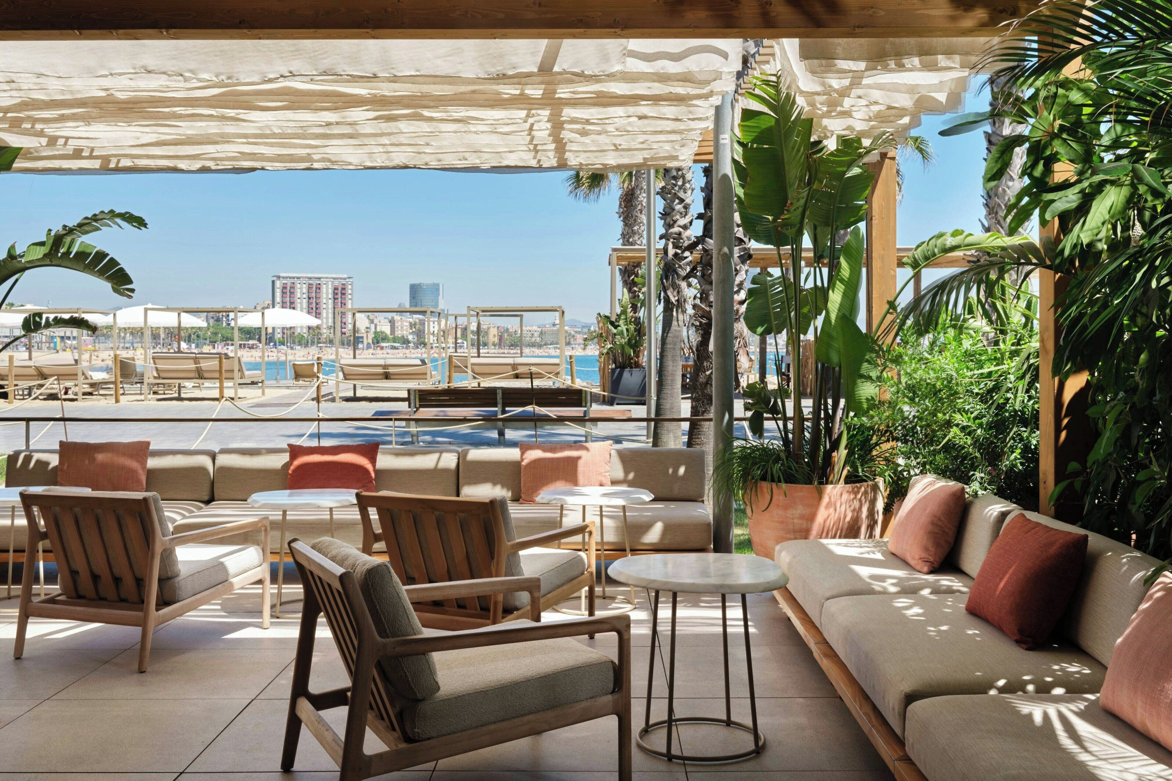 A poolside lounge with seating arrangements, a view of the pool, and tropical plants.