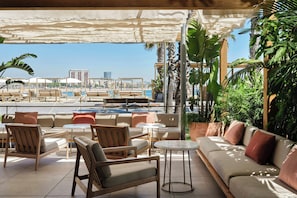A poolside lounge with seating arrangements, a view of the pool, and tropical plants.