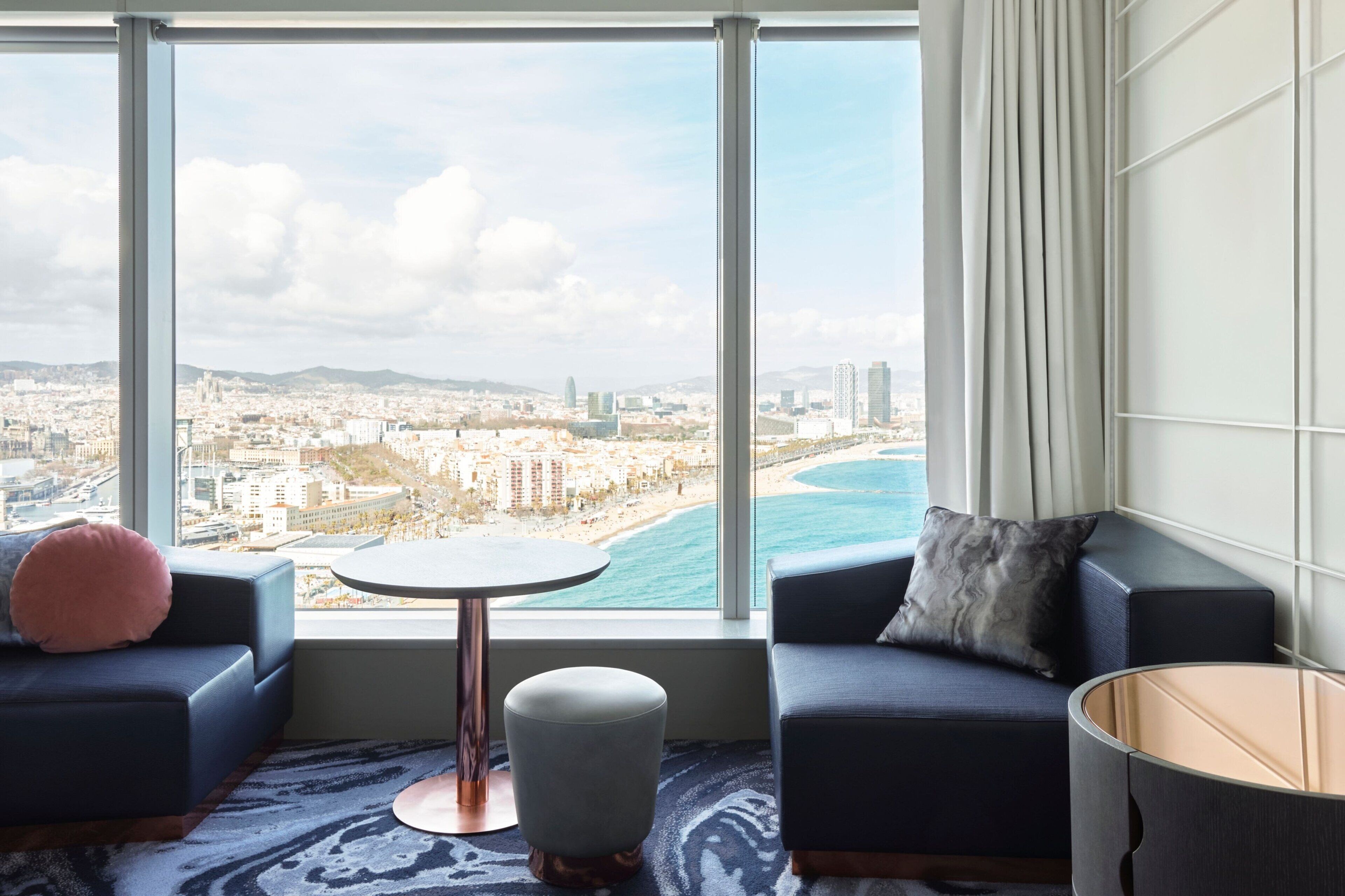 A modern living room with a large window, a round coffee table, and two sofas.