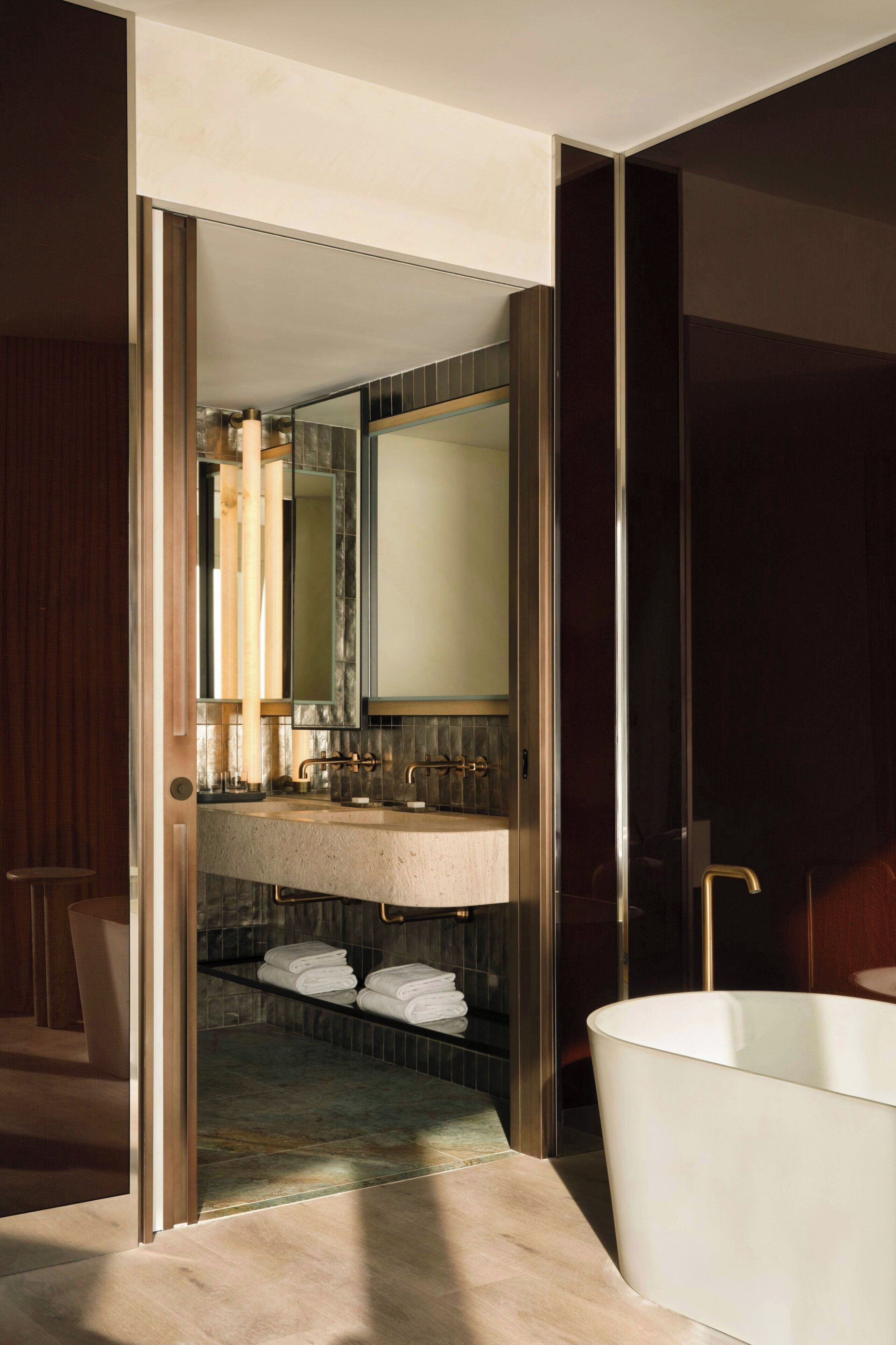 Un baño moderno con un espejo grande, una bañera y un tocador con lavabo.