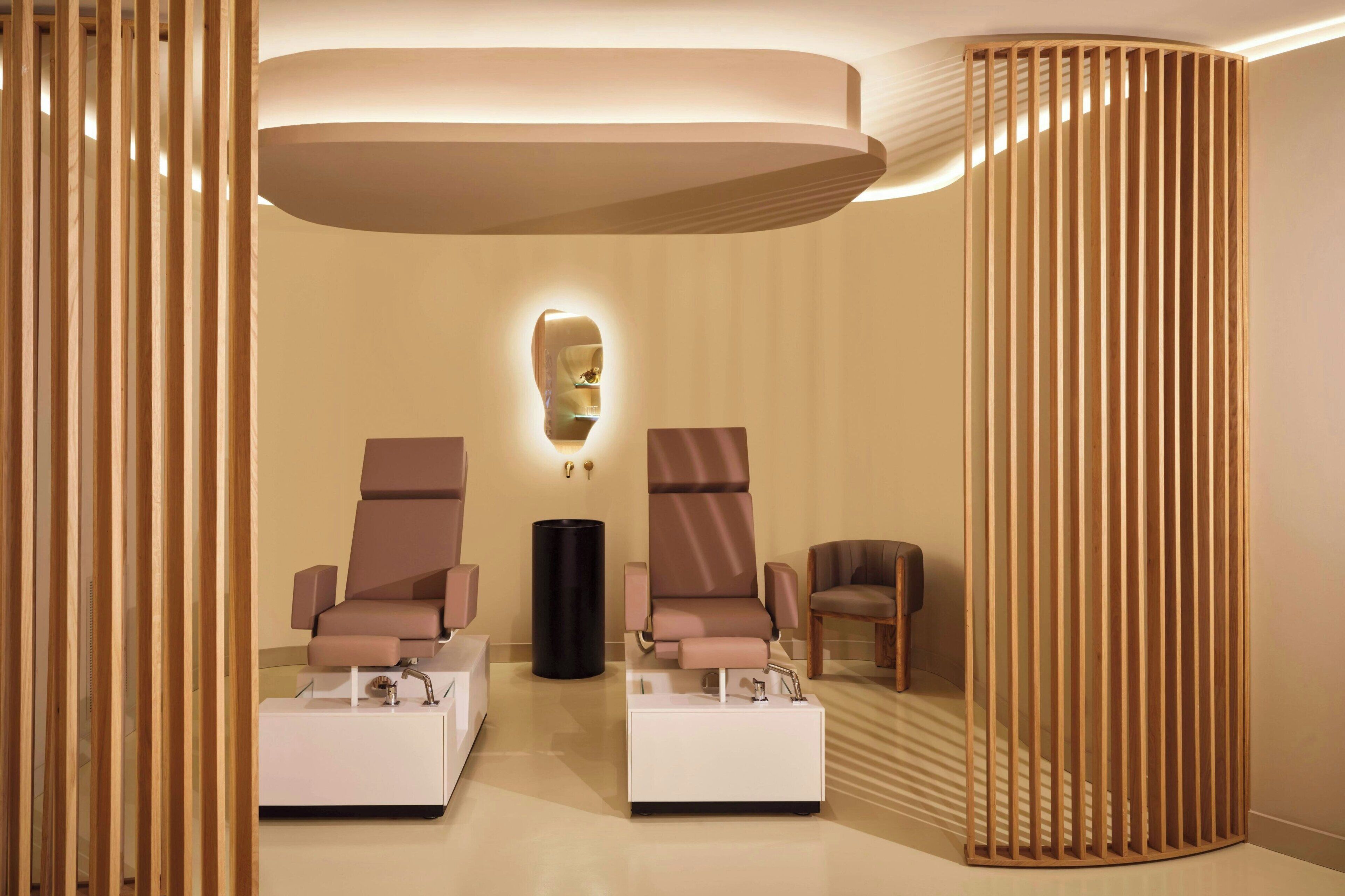 A modern spa room with two massage chairs, a small table, and a decorative wall piece.