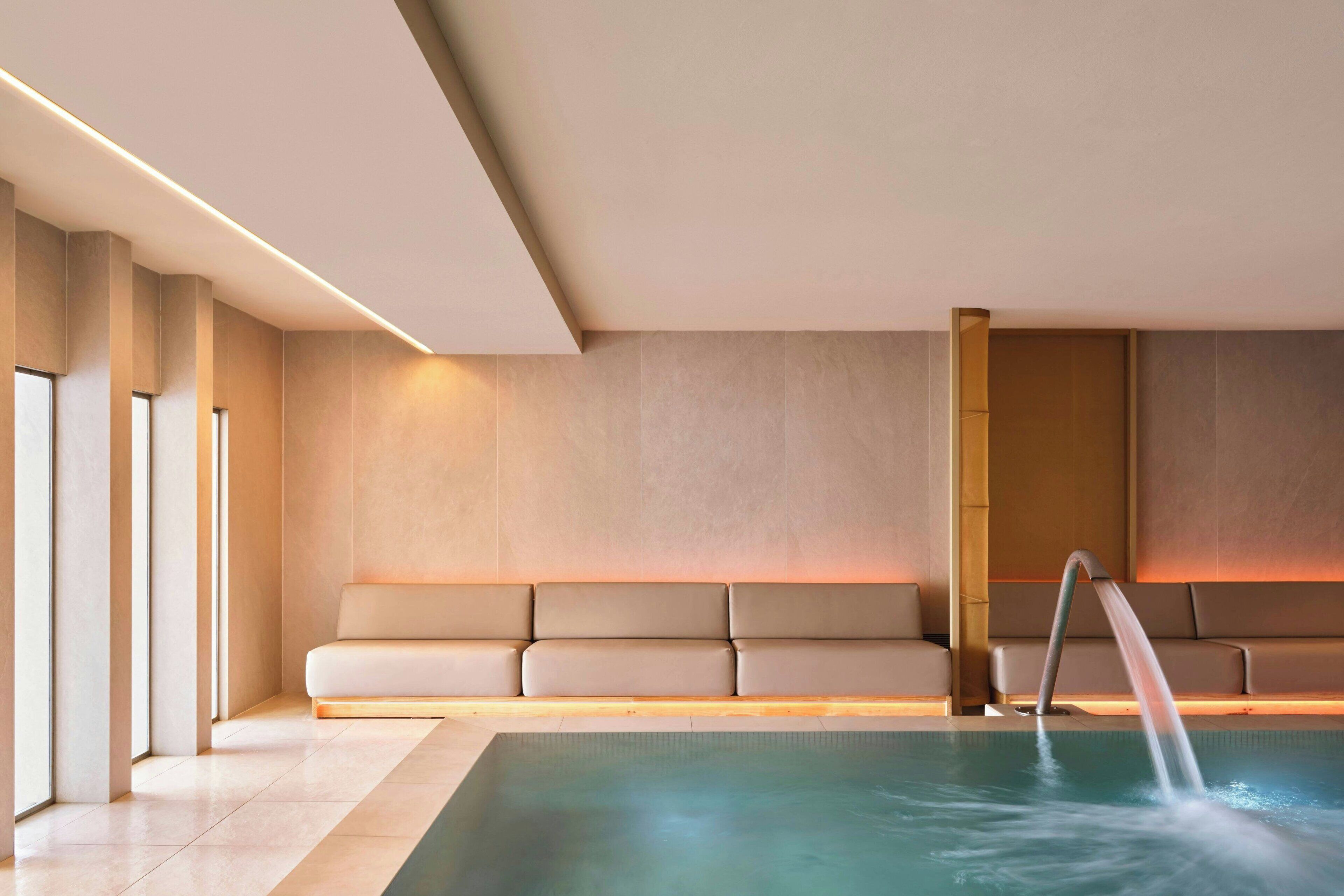 Un área de piscina interior moderna con un banco y una fuente de agua.
