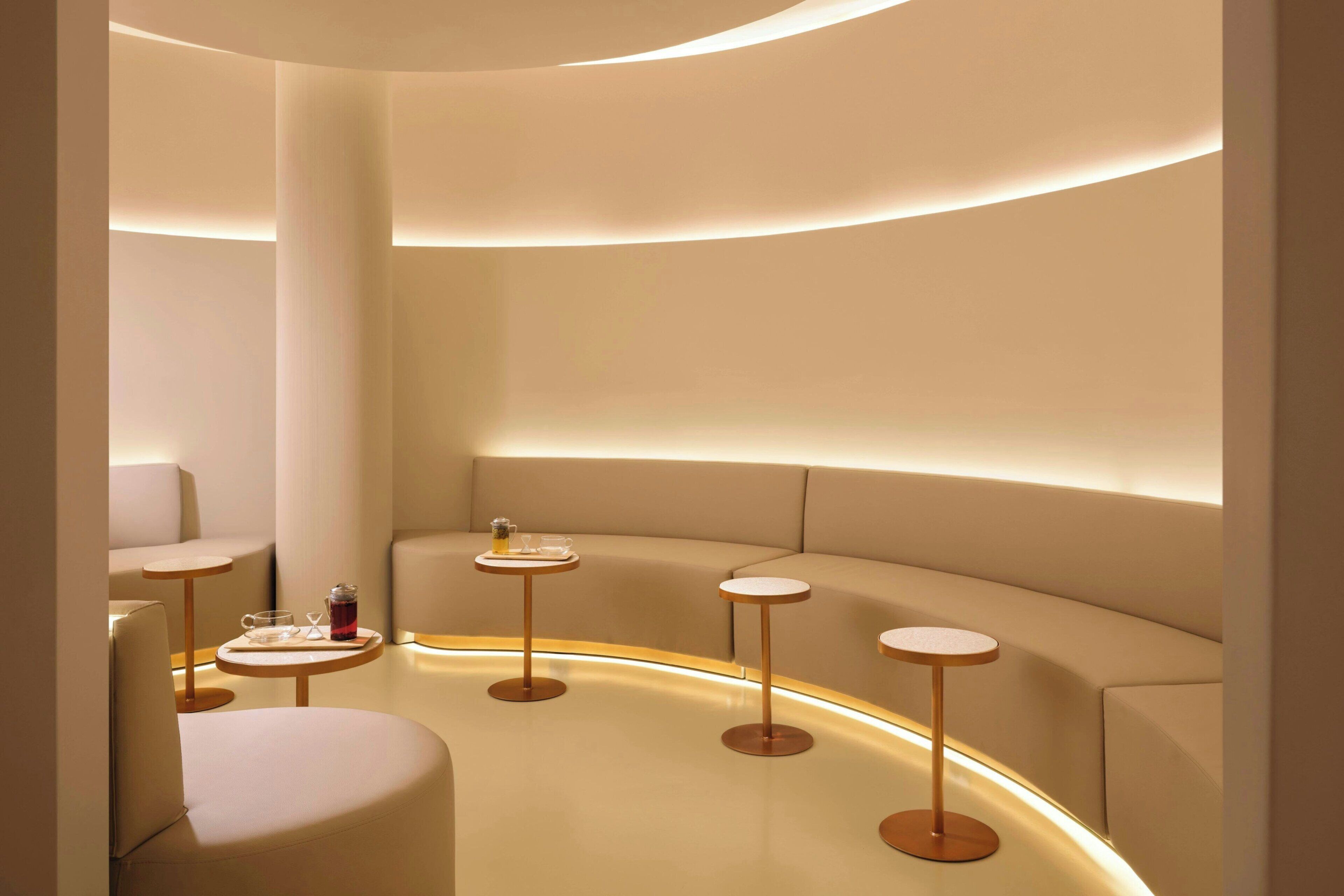 A modern interior with a curved seating area, round tables, and a minimalist design.