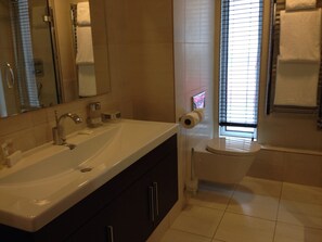 Ett badrum med handfat, spegel, toalett och fönster.